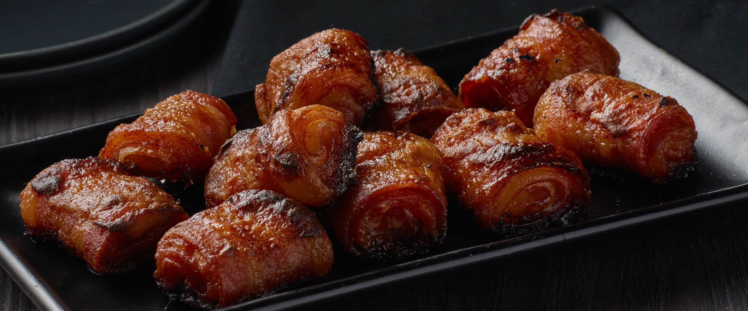 Rolled Bacon Bites on black plate