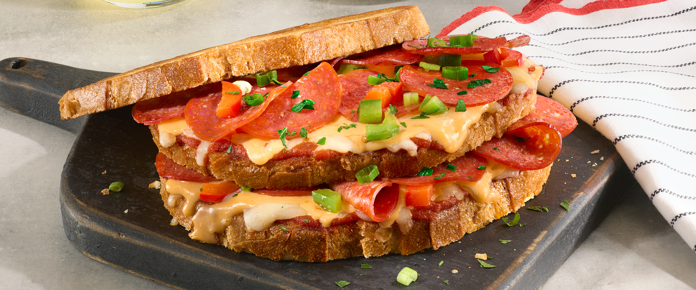 Double decker grilled cheese sandwich with pepperoni with diced green and red peppers